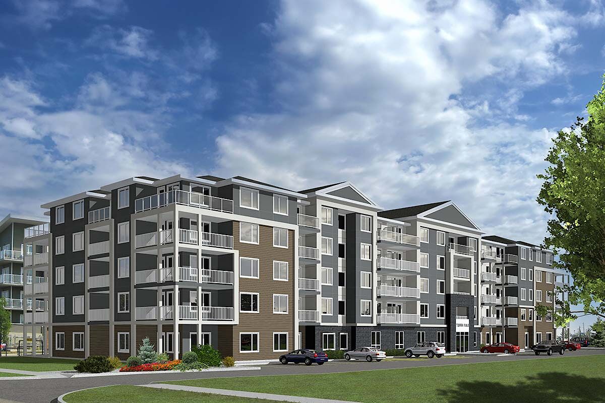 Modern four-story apartment building with balconies, parked cars, and partly cloudy sky.