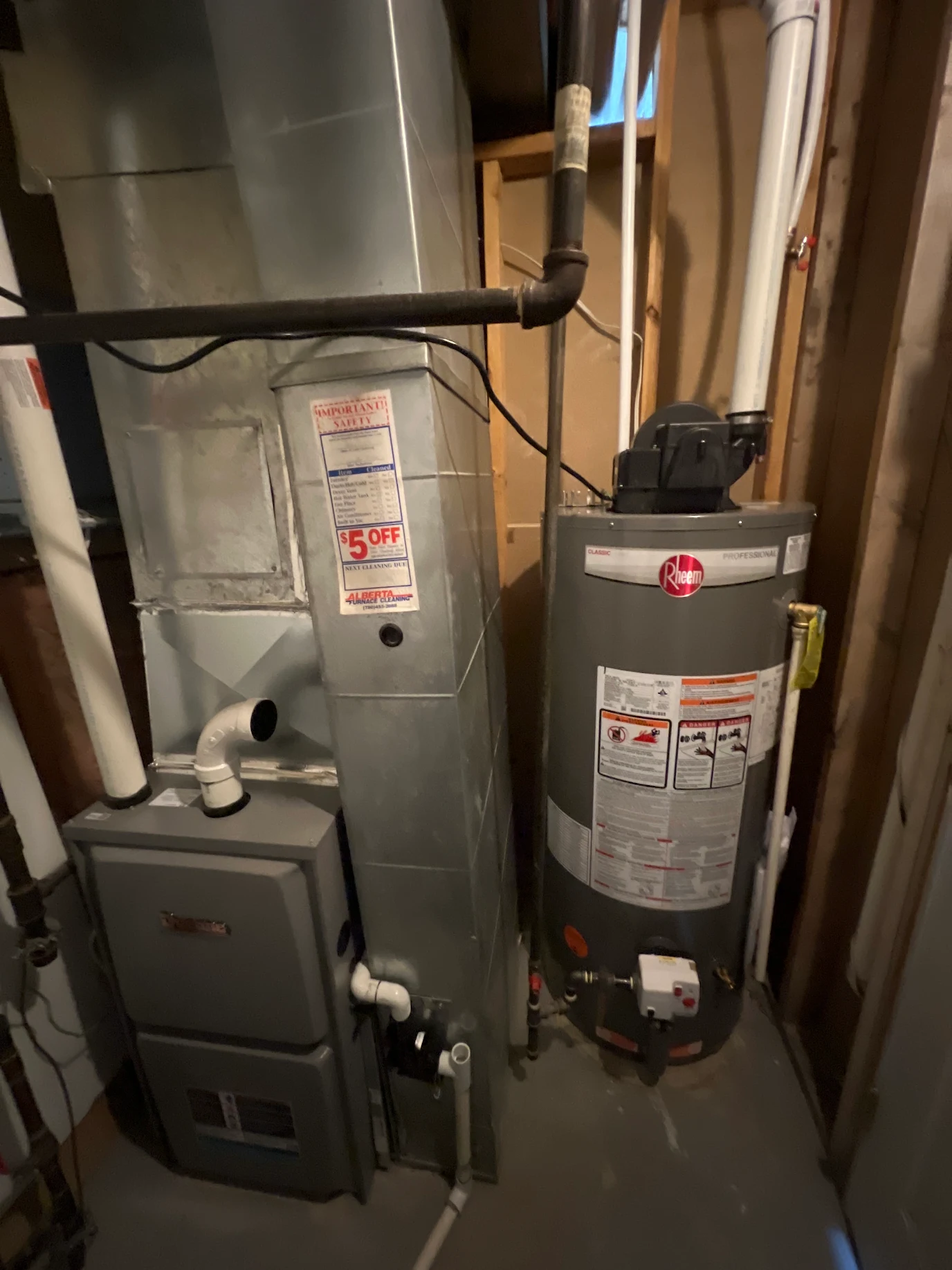 A Rheem water heater and furnace unit installed in a basement with metal ductwork and pipes.