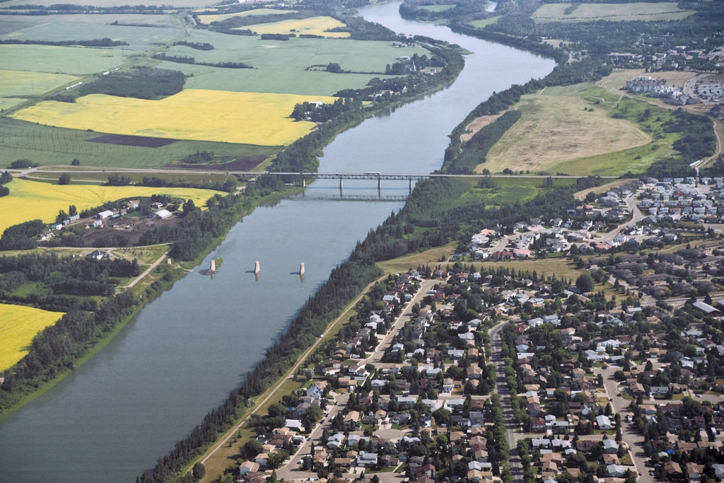 Aerial view of a town by a river with bridges, farmland, and houses.