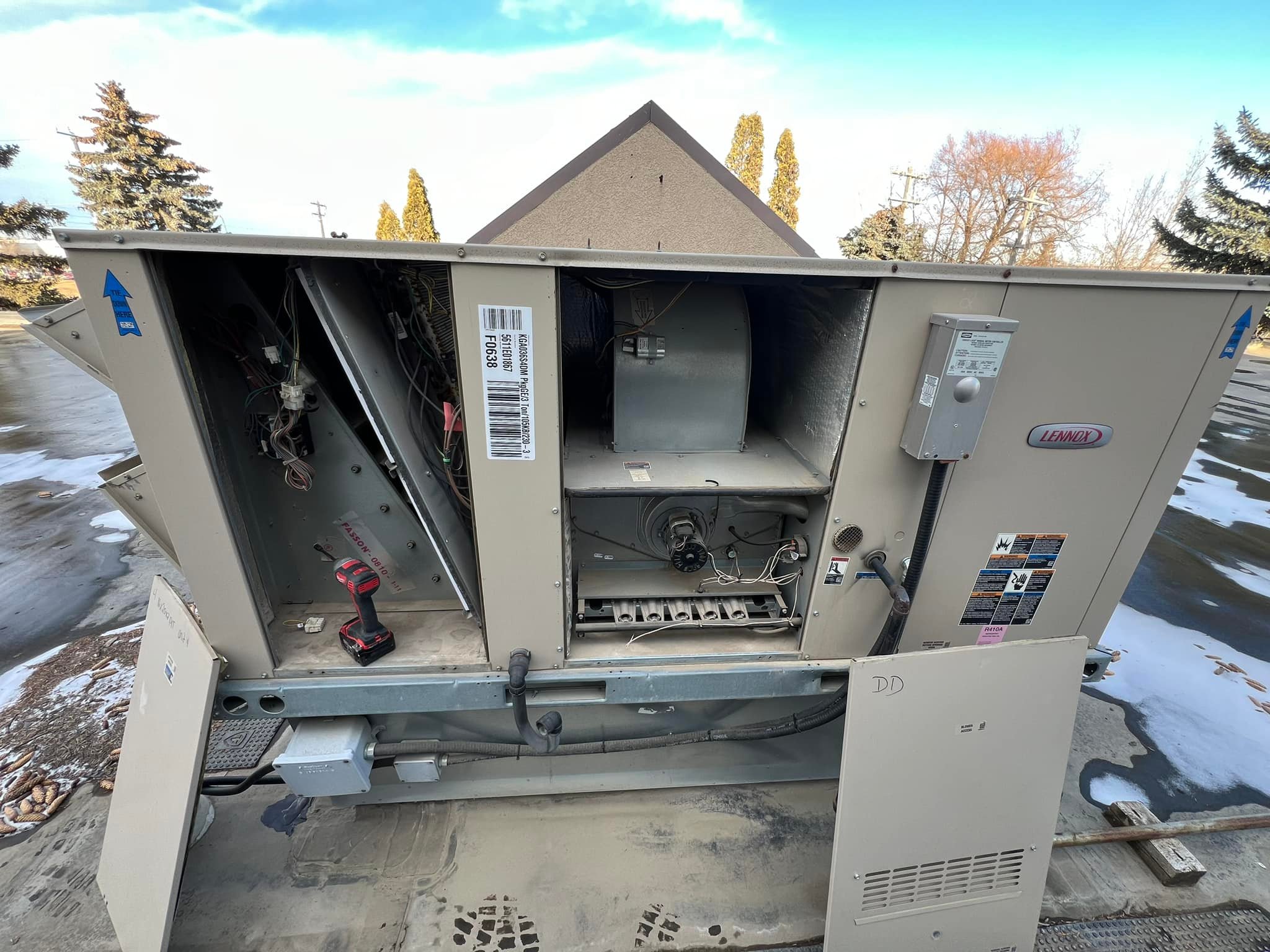 Open commercial Lennox HVAC unit showing internal wiring and components on a concrete rooftop.