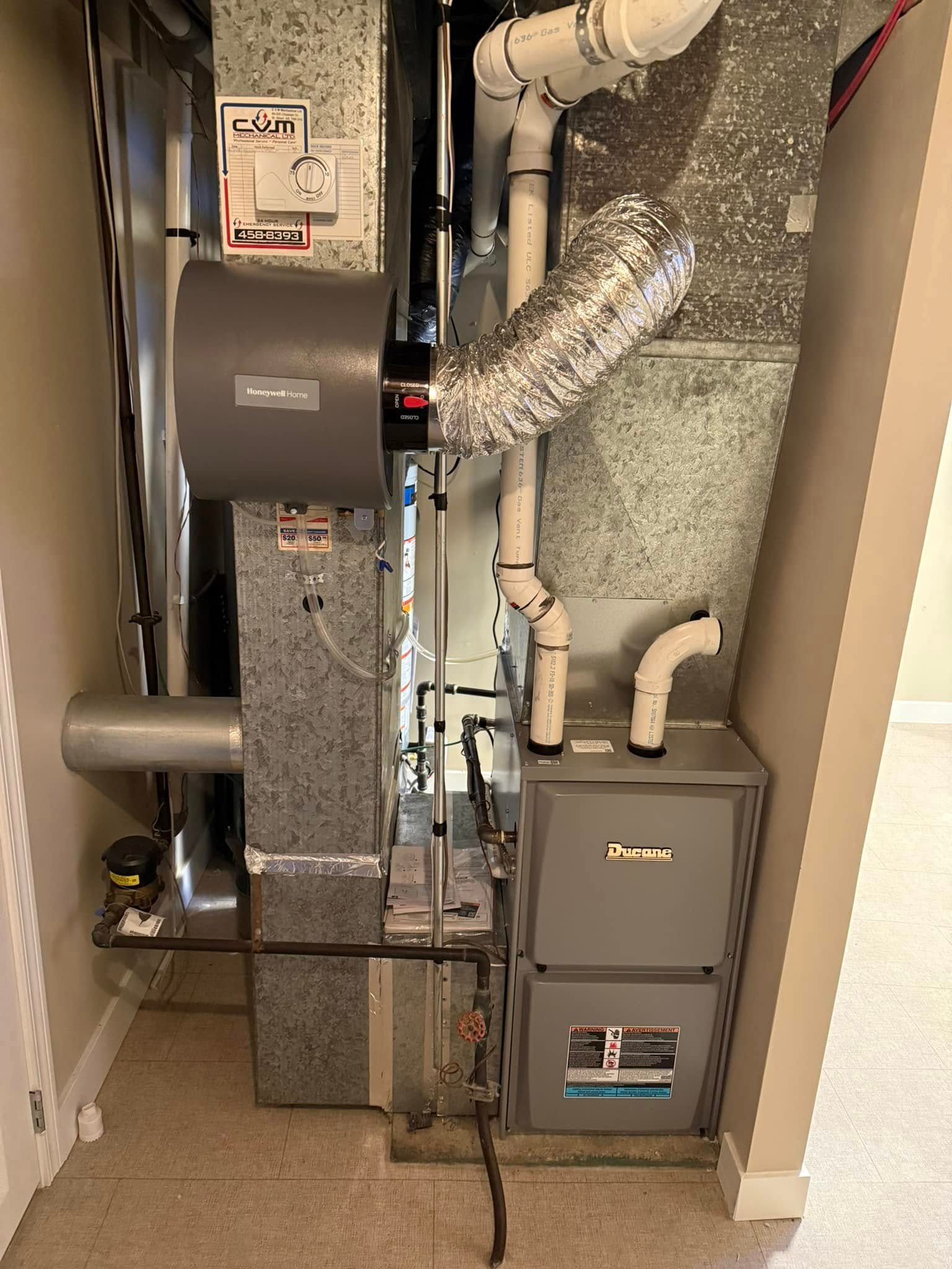 Indoor furnace and HVAC duct system with silver flexible vent and pipes in a home utility space.