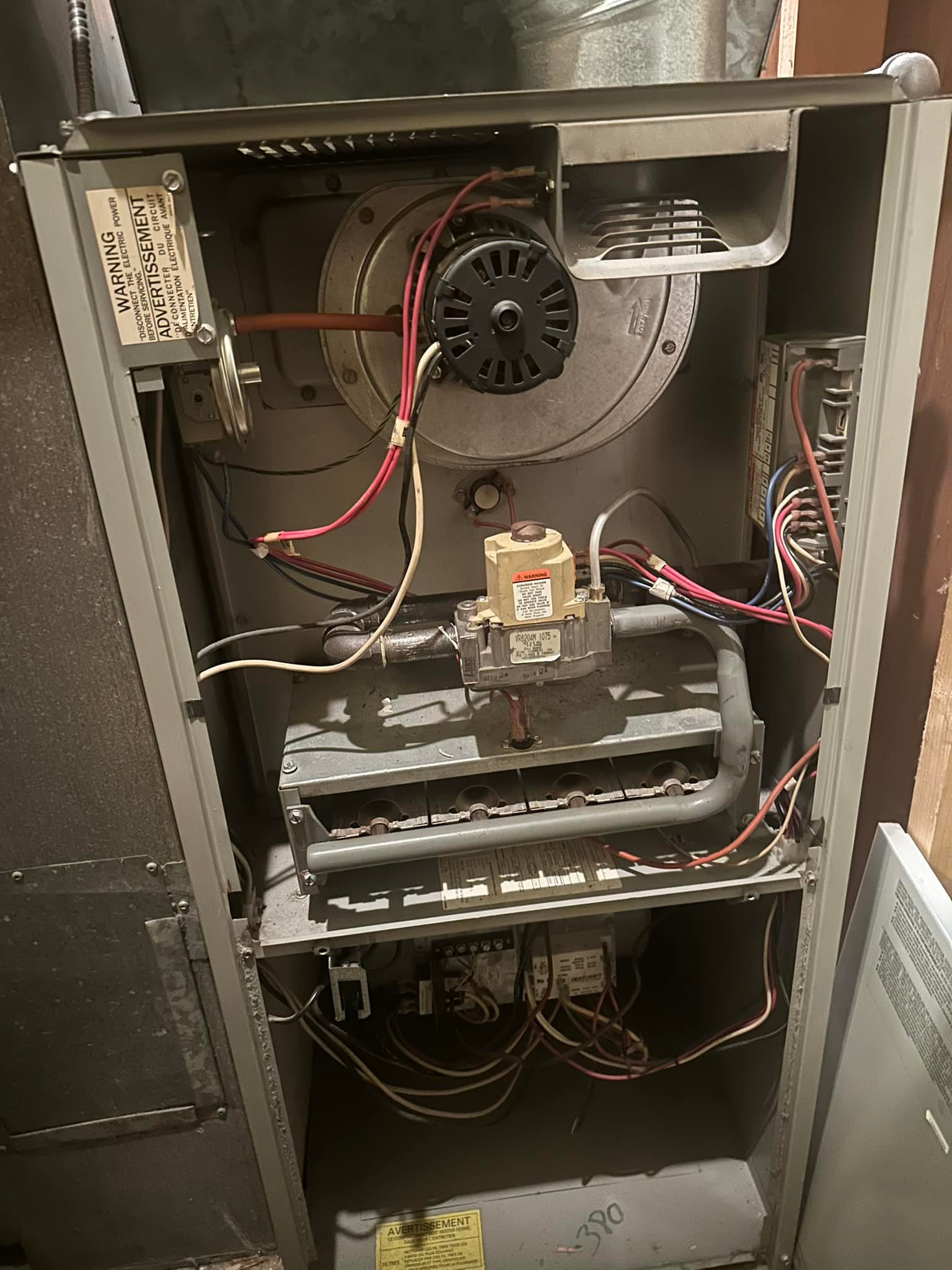 Open furnace showing internal wiring, gas valve, burner assembly, and fan blower components.