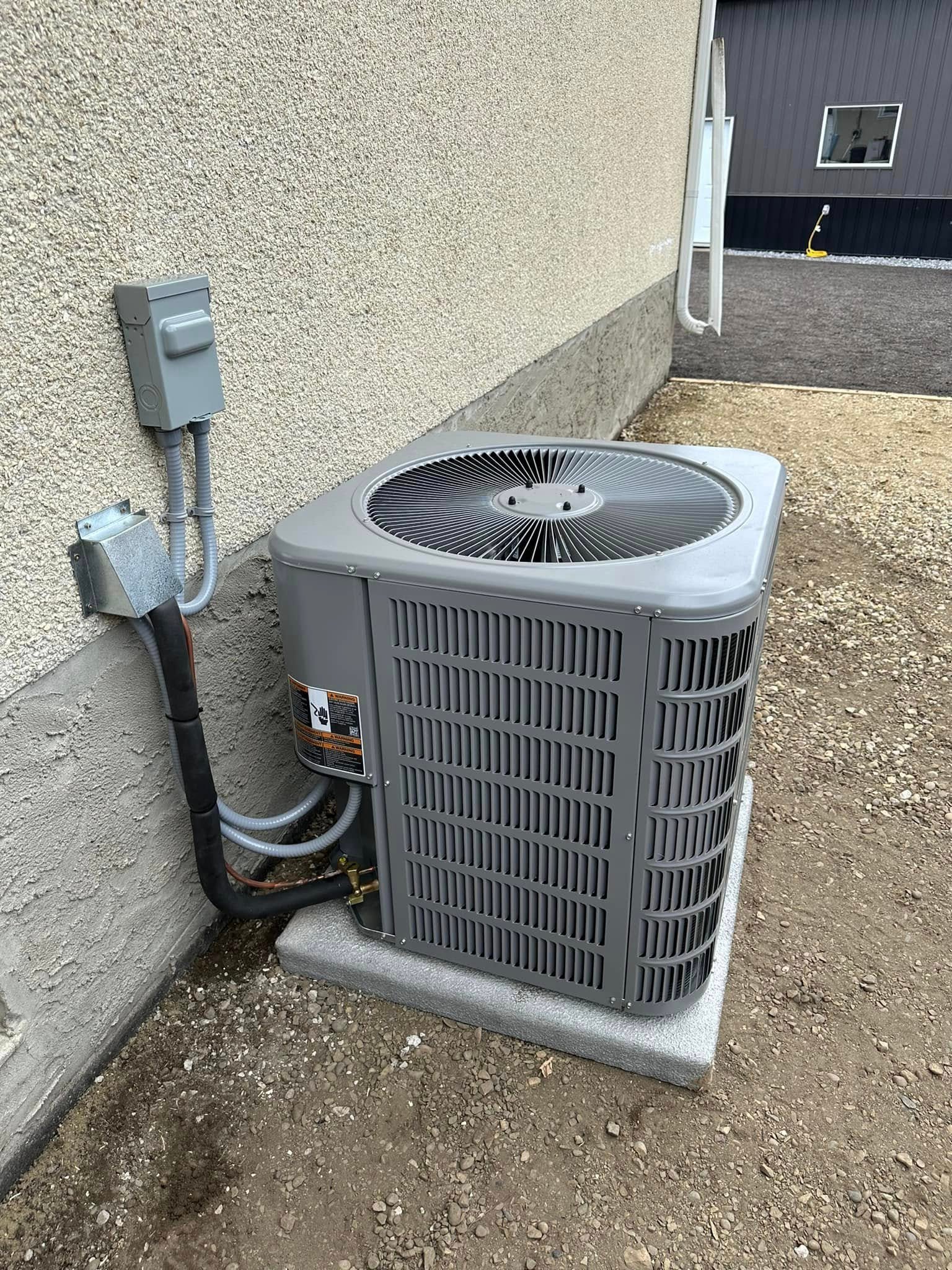 Outdoor gray air conditioning unit installed on concrete slab beside a beige stucco house wall.
