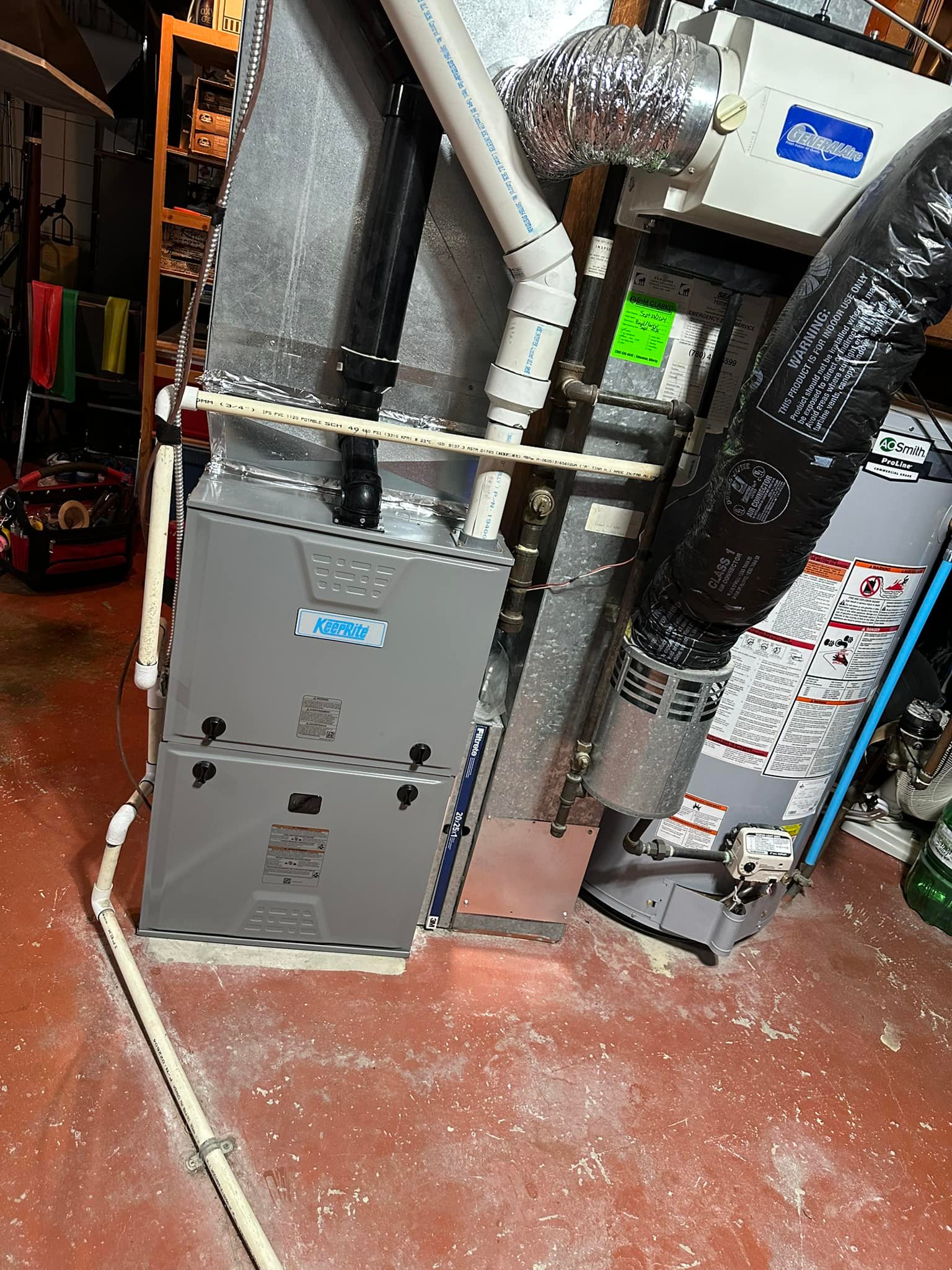 Basement furnace and water heater with pipes and ducts on a red concrete floor.